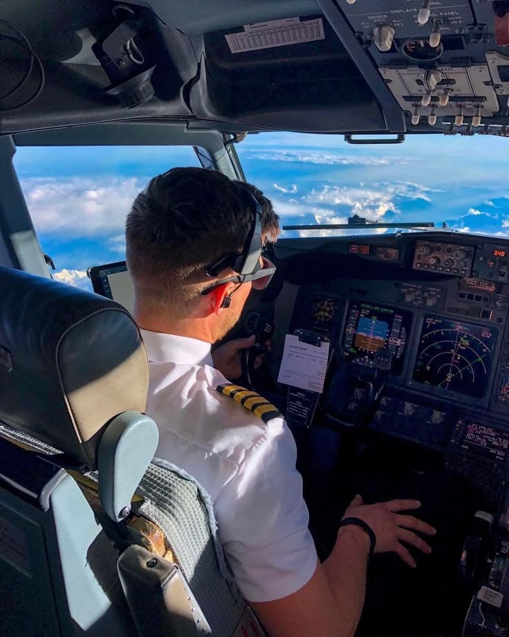 Pilot seated in a cockpit with a wide sky view ahead.