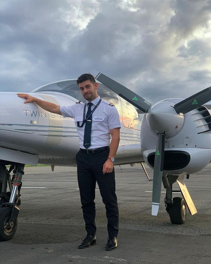 Pilot standing beside a twin-engine training aircraft on the apron.