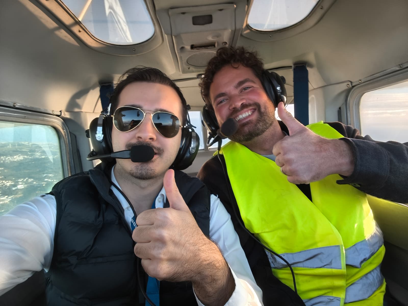 Three passengers and a pilot giving thumbs up in the cabin